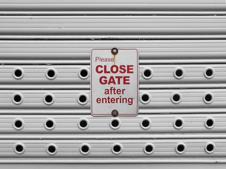 please close sign on a light grey painted perforated roll up gates background                               の写真素材