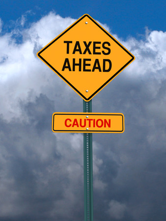 conceptual post sign caution taxes ahead sign over dramatic skyの写真素材