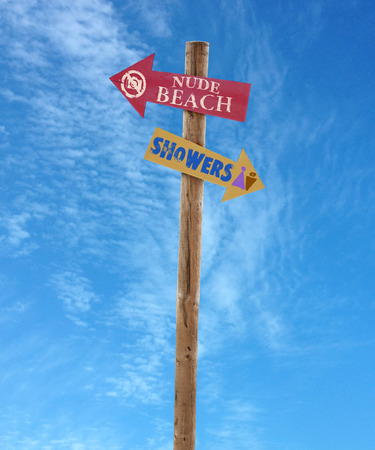 wooden arrow direction signs post to the nude beach and showers against a blue skyの写真素材