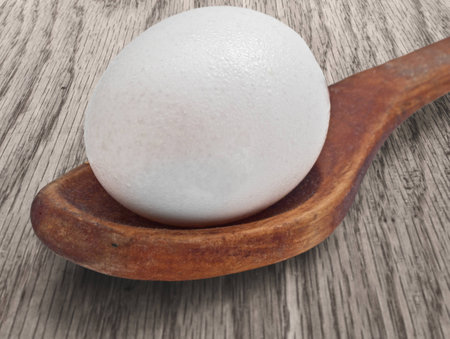 vintage wooden spoon with egg on the tableの写真素材