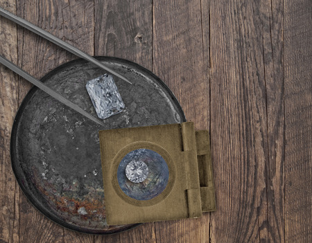 two diamonds in a vintage tin, tweezers and loupe on a wooden bench,
space for your textの写真素材