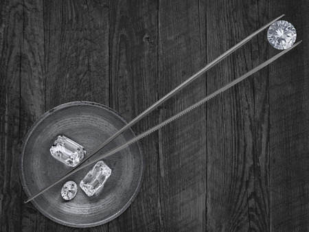 monochromatic image of a various cut  diamonds in a working  brass tray and  tweezersの写真素材