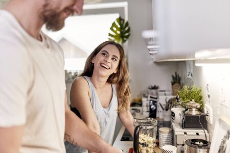 cute caucasian couple spending their morning in the kitchen, prepairing a smoothieの写真素材