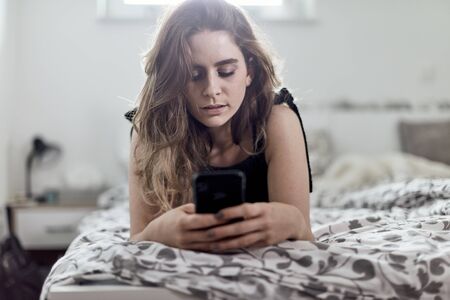 young brunette and her smart phone.smiling at the cameraの写真素材