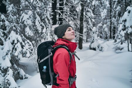 young caucasian woman spending her free time hiking outdoors in nature, covered with snow.の写真素材