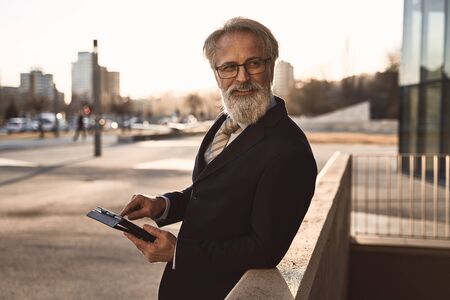 caucasian senior CEO using a smartphone and smart tablet