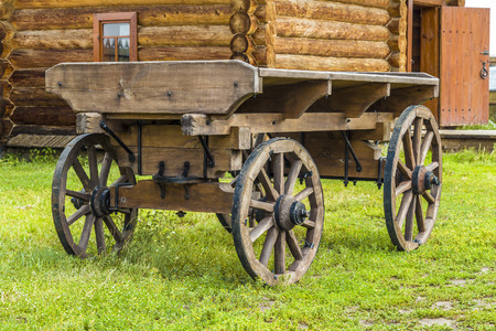 An old wagon in the yard of the rural wooden house.の写真素材