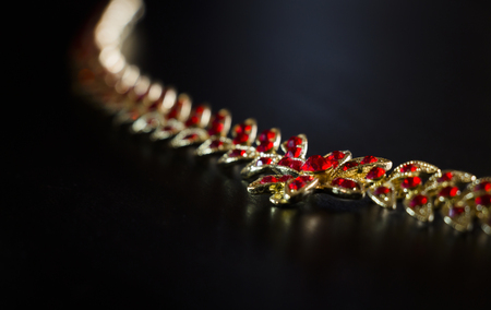 Gold necklace with red stones close-up on a black backgroundの写真素材