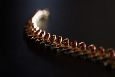 Gold necklace with red stones close-up on a black backgroundの写真素材