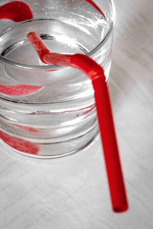 Red straw in a glass of water close-up.の写真素材