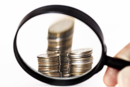 Coins through a magnifying glass closeup on a white background.