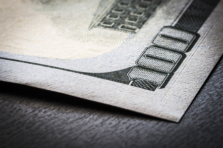 A fragment of a 100-dollar bill on a black table close-up.の写真素材