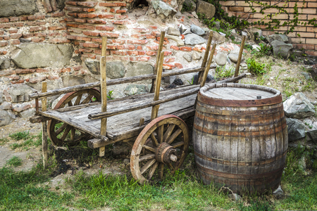 The abandoned cart and an old wooden barrel in the backyard.の写真素材