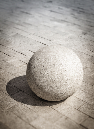A large stone ball lies on a stone pavement.の写真素材