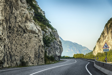 A sharp turn of a mountain road with a gray asphalt pavement.