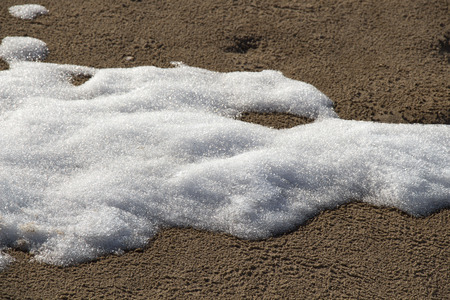 Snow spots on the sand of the river bank close-up.の写真素材