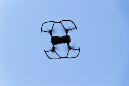 The black quadrupter flies against the blue sky.