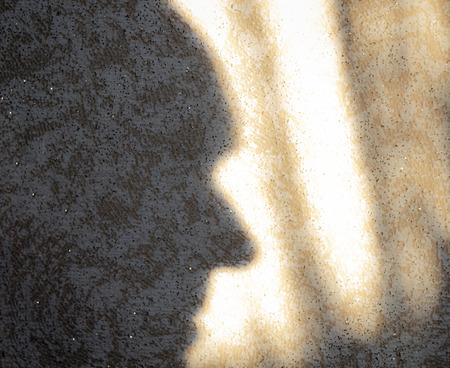 The contour of the shadow of the face on the wall, illuminated by the sun.の写真素材