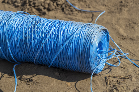 A string of blue synthetic rope in the sand.の写真素材