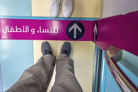 Dubai, UAE - December 3, 2018: A red line on the floor of a Dubai subway car bounding a female car.