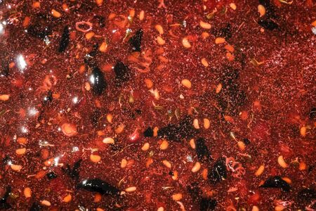 Cooking raspberry jam in a large pan.