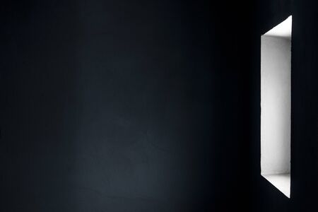 Light from the window to the wall of a gloomy room with concrete walls.の写真素材