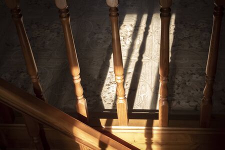 Element of a wooden interior staircase. Wooden baluster close-up.