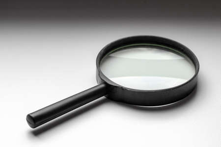A black magnifier lies on a white windowsill.の写真素材