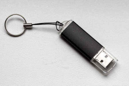 Black flash drive lies on a white windowsill close-up.