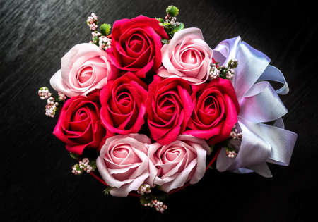 A basket with artificial flowers on a dark background close-up.