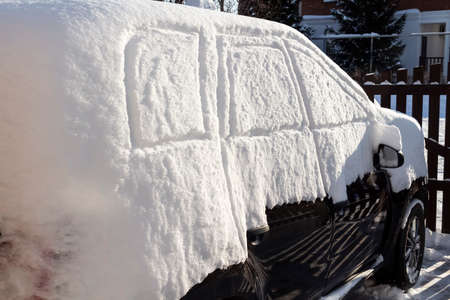 The car was completely covered with snow in the backyard.の写真素材