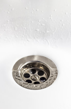 Close-up of a drain hole in a white ceramic sink.