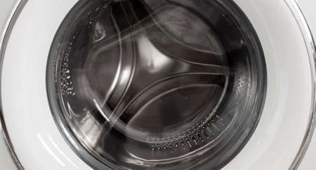 Chromed drum of a washing machine with an open lid.