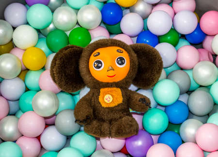 A small toy teddy bear lies in a box with colorful balloons.の写真素材