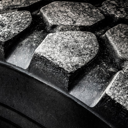 Tread of a partially worn truck tire close-up.