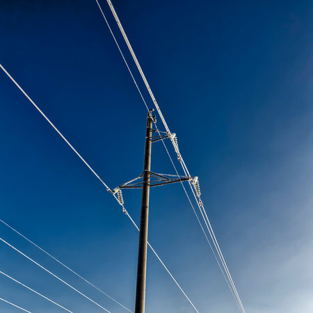 High-voltage wires and poles are covered with frost on a frosty winter day.の写真素材