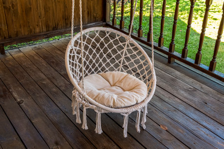 A white hammock chair hangs on the wooden deck of a private house.の写真素材