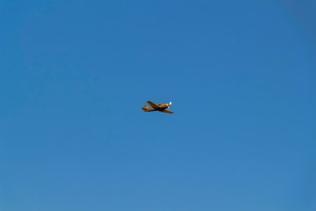 A sporty orange airplane against a clear blue sky.の写真素材