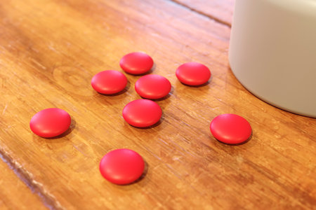 The remains of red oval pills are scattered next to the empty bottle.の写真素材
