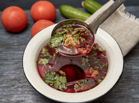 Beetroot soup with beef , vegetables and tomatoes on a wooden table top . Rustic style .の写真素材