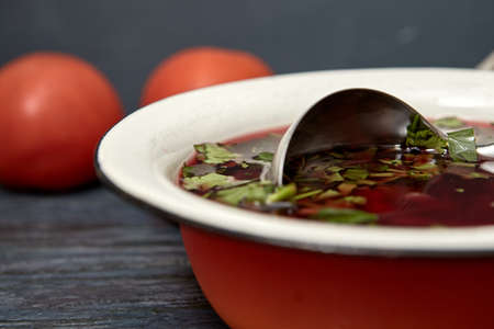 Beetroot soup with beef , vegetables and tomatoes on a wooden table top . Rustic style .の写真素材