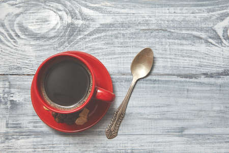 Red cup of coffee on gray wooden table with spoon . Blurred background . Toned . Top view.の写真素材