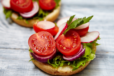 Healthy food concept. Tasty homemade sandwiches with tomato, onion, radishes, parsley, on a wooden gray boardの写真素材