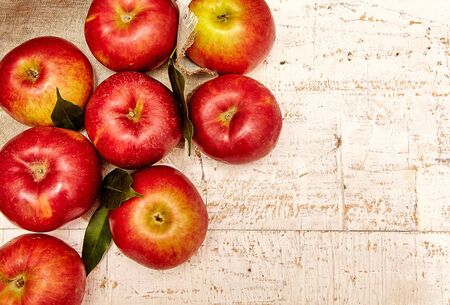 Fresh red apples with green leaves and linen napkin on rustic background. Free space for text. Top viewの写真素材