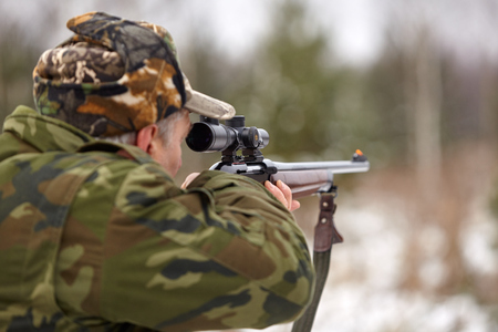 Hunter in camouflage clothes with hunting rifle.
