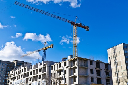 Building crane on the background of blue sky and of the house under construction