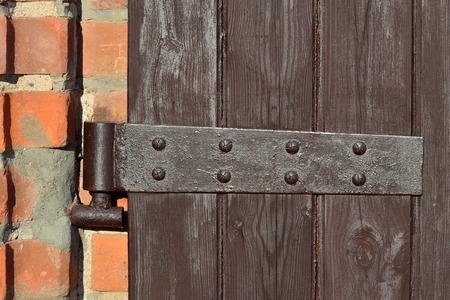 Antique door hinge on wooden door closeup