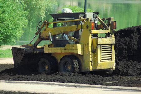 Mini excavator-grab working in city park  at the springの写真素材