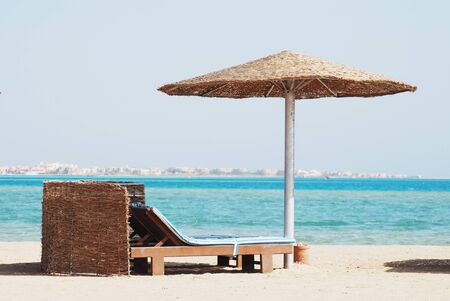 empty beach chair with straw sunshade at the seaの写真素材