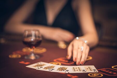 The girl laid out cards in a casino. game table, glass, cognac. Focus on the cards.の写真素材